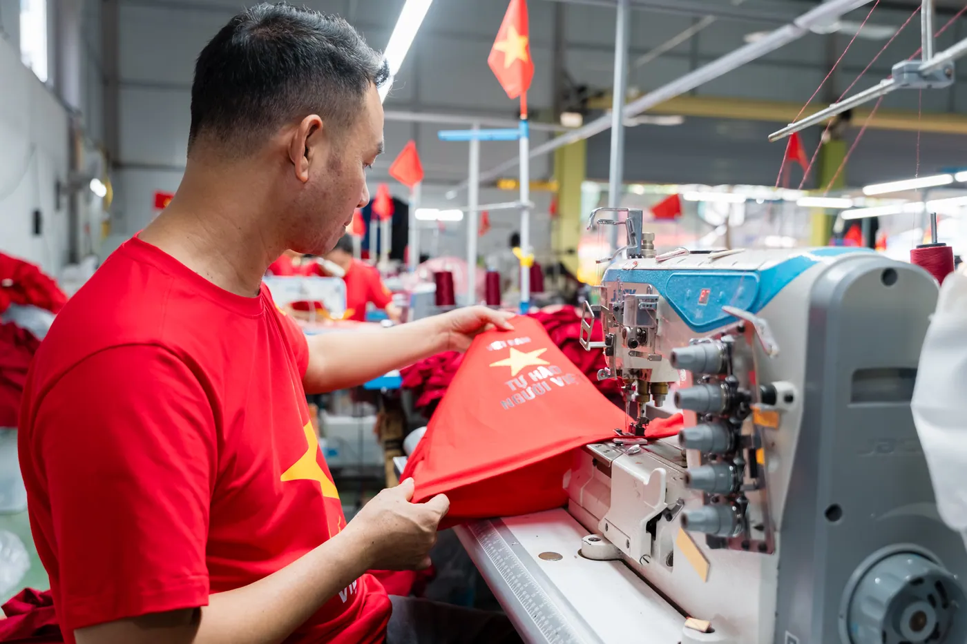 Thợ may ráp áo thun đồng phục trên máy vắt sổ tại xưởng QUYN